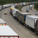 A police vehicle drives past lorries are backed up on the M20 motorway which leads from London to the Channel Tunnel terminal at Ashford and the Ferry Terminal at Dover, June 23, 2015.